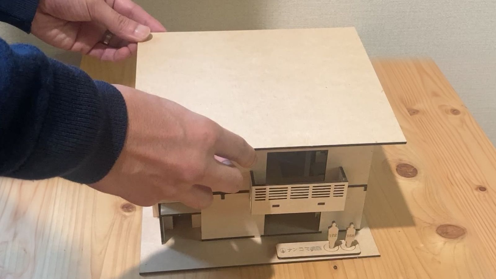 1/50の模型の屋根を、手で持ち上げて外しているところ